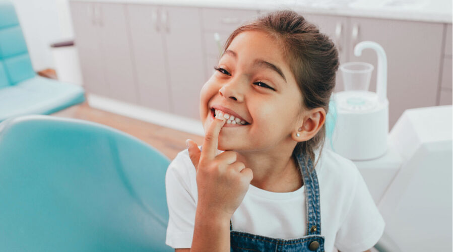 Photo of girl smiling and point at her teeth