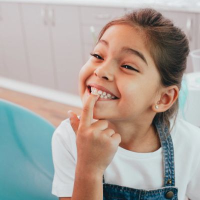 Photo of girl smiling and point at her teeth